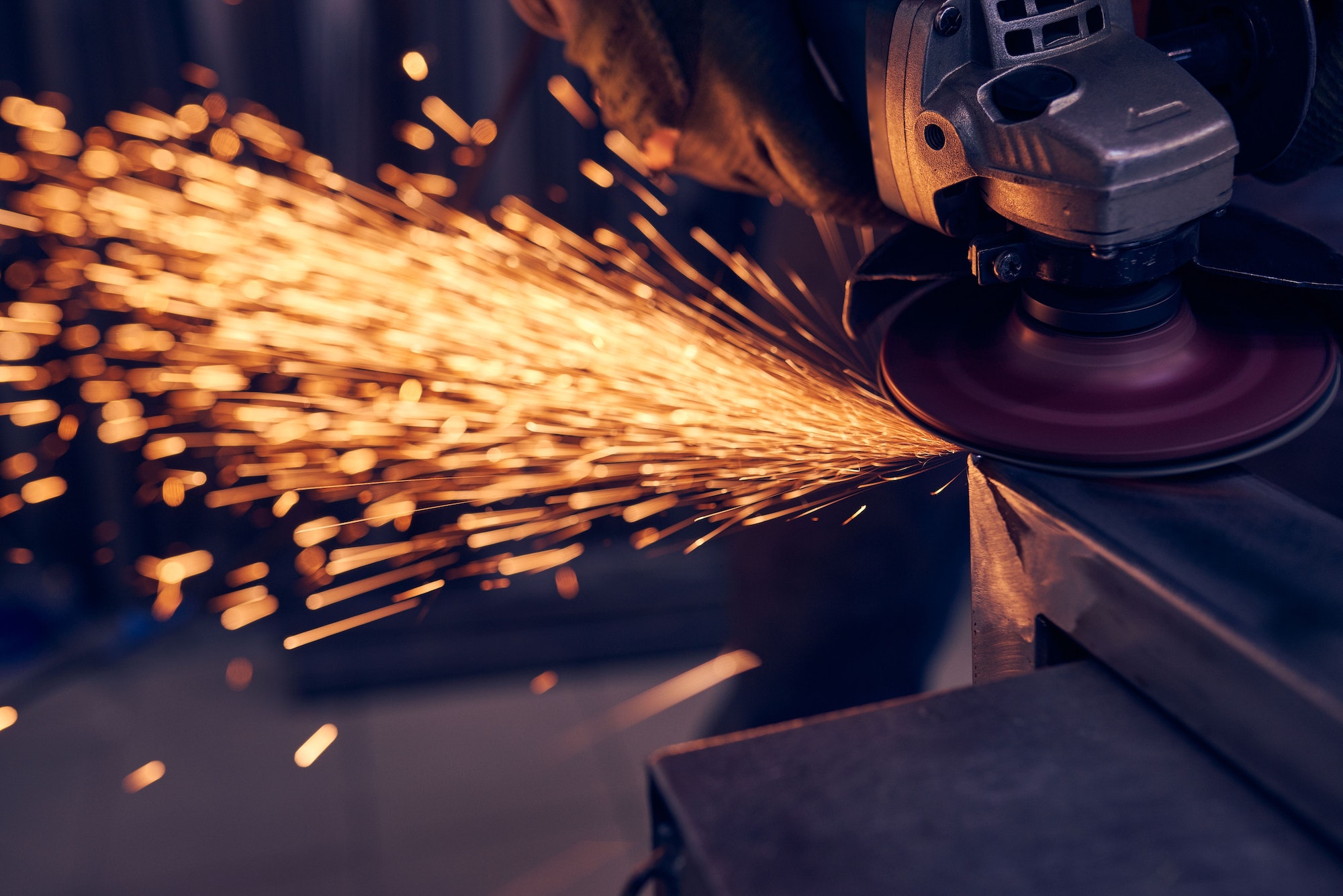 Worker cutting metal with grinder. Sparks while grinding iron